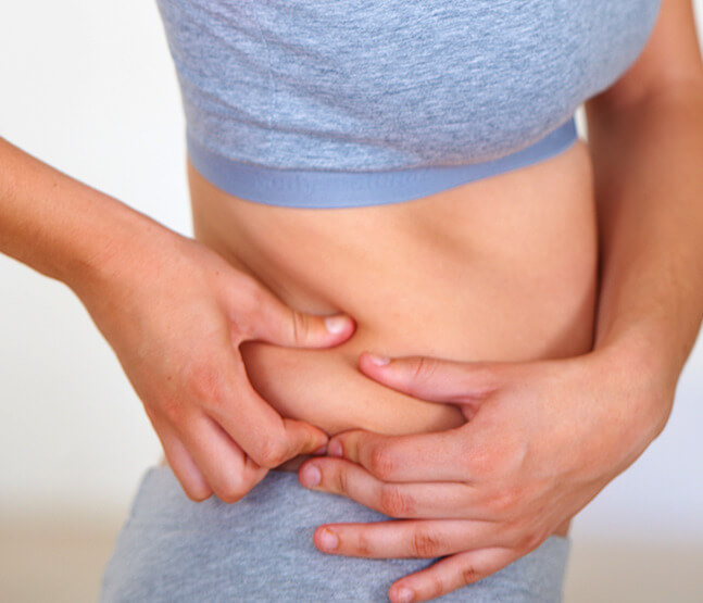 Frau greift seitliches Bauchfett als Symbolbild für Behandlung von Love Handles